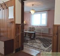 An elongated interior of a family house with wooden paneling and carpets.