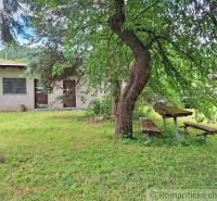A small cottage with garden seating, surrounded by greenery, ideal for plots - living.