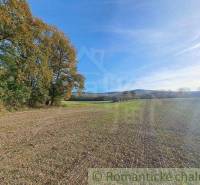 In the picture, there are green recreational plots with views of hills and trees.
