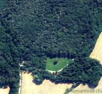 An aerial view of a dense forest surrounded by fields, ideal for recreational properties.