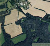 An aerial view shows a plot of land for sale amidst fields and forests for recreational purposes.