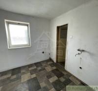 A room with tiles, a sink, a simple window. The family house needs interior renovation.