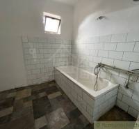 A bathroom with a bathtub and older tiles, a base for renovation in a family house.