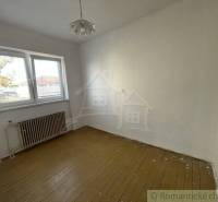 An empty room with wooden flooring, a radiator, and a window, and a family house.