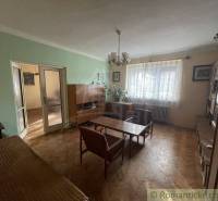 A living room in a family house with older furniture and wooden flooring.