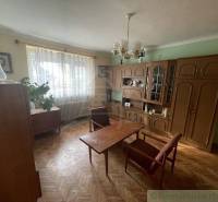 Living room in a family house with antique furniture, parquet flooring, and curtains.