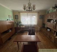 A room in a family house with wooden furniture, houseplants, and curtains on the window.
