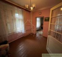 A room with a wooden floor, curtains, paintings, and light in a family house.