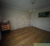 A dark room in a family house with parquet flooring, a painting, and cardboard boxes in the corner.