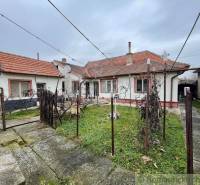 A family house with a red roof, a yard with a lawn, and a concrete walkway.