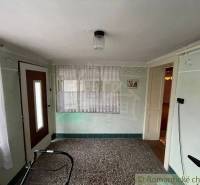 The interior of the hallway has light walls, a carpet, doors, and a window with a sheer curtain. Family house.