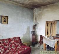 A room with a retro sofa, an old tiled stove, family photographs, and furniture.