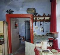 An older rural interior with kitchenware, a spice rack, and curtains in a family house.