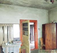 A room in a family house with older furniture, a wooden wardrobe, and open doors.