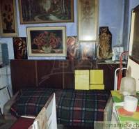 A room full of paintings, old furniture, and decorations in a village family house.