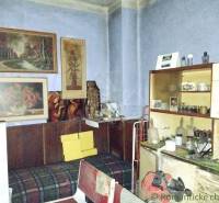 A room in a family house with vintage furniture, paintings, and shelves full of trinkets.