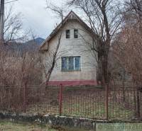 An old family house is surrounded by trees and a fence.