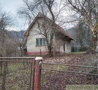 A family house surrounded by trees, a fence, and fallen leaves, a peaceful natural environment.