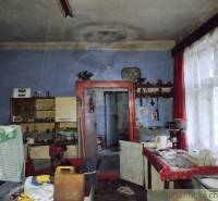An old family house with blue walls, curtains, and antique furniture in the interior.