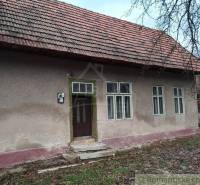 A family house with plaster, windows, and wooden doors under a pitched roof.