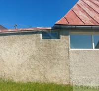 A family house with a gable roof, plaster, and a grassy area, on a sunny day.