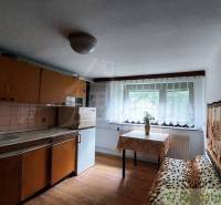 A simple kitchen in a family house with a window, table, and sofa.