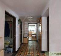 A hallway in a family house with a tiled pattern on the floor, leading to a sunny room.
