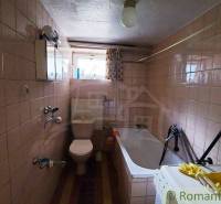 A bathroom in a family house with a bathtub, a sink, white tiles, and a window.
