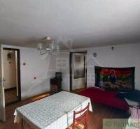 A room in a family house with a dining table, a blanket on the wall, and a cross.