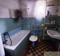 Bathroom with a bathtub and a sink, part of a family house, also includes a radiator.