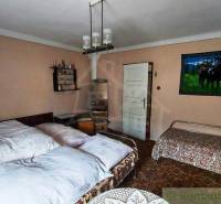 A bedroom in a family house with a painting of horses, one double bed, and one single bed.