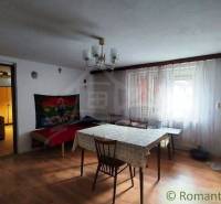 Dining room with a wooden table, chairs, fireplace, leading to the bedroom and family house.