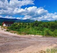 A landscape with a house and recreational land surrounded by mountains and a sky with clouds.