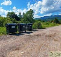A rural landscape with waste containers, surrounded by greenery, suitable for living and plots.