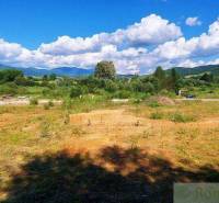 A grassy area and a house, mountains in the background, an ideal location for recreational plots.