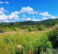 Hilly landscape with forests and recreational areas, blue sky with clouds.