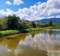 Green trees and a river with clouds, mountains, recreational areas ideal for relaxing by the water.