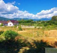 A meadow, houses, hills, clouds, and recreational properties in a picturesque natural setting.