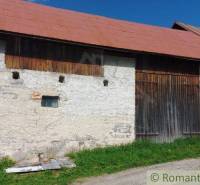 The image shows an old shed with a wooden gate and stone walls.