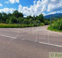 A road with a view of fields with nature and mountains in the distance.