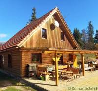 A cottage in nature with wooden decor, a large terrace, and a grill in the countryside.