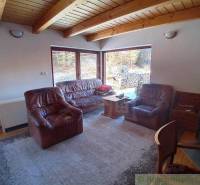 A living room in a cabin with a wooden ceiling and leather furniture.