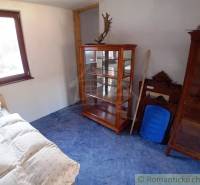 A room in a cottage with a bed, a display cabinet, and wooden furniture with a natural atmosphere.