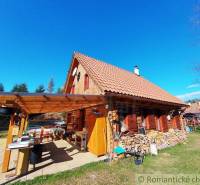 Traditional wooden cottage in the countryside with a terrace, surrounded by nature and wood.