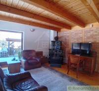 A cottage with terrace access, leather armchairs, a television, vintage stove, and wooden ceiling.