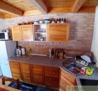A kitchen in a cabin with wooden cabinets and equipment on a brick wall.