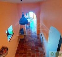 A hallway in an ancient house with peculiar architectural openings and a vaulted ceiling.