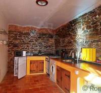 A kitchen with a unique design, stone walls, wooden details, and a rustic atmosphere.