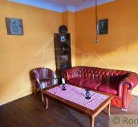 A room with a leather sofa and armchair, yellow walls, wooden table and floor, peculiar properties.