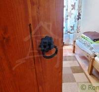 A rustic furnished room with a wooden bed and heavy doors, peculiar properties.